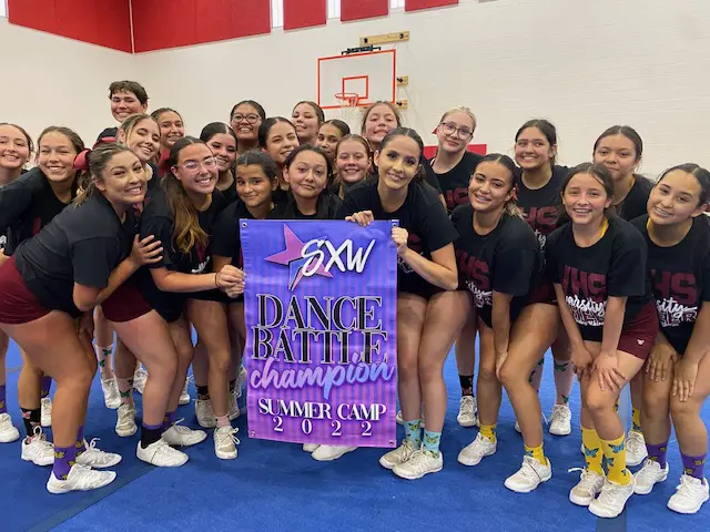 A group of girls holding up a sign for the dance battle champion.